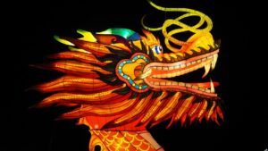 Cabeza de dragón luminoso en linterna artística naranja y roja, detallada y festiva, que representa simbolo dragon descubre significado