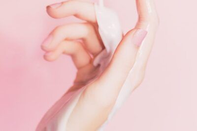 Mano con crema sobre fondo rosa que significa color verde limon brillante suave
