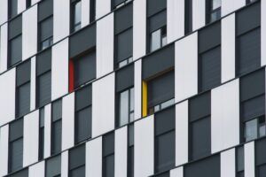 Fachada moderna con paneles blancos y grises y ventanas con marcos rojos y amarillos que plantea que significa color verde musgo en el diseño