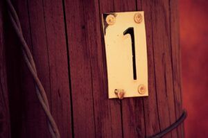 Placa con el número uno fijada en un poste de madera que significa el numero descubre su significado y simbolismo
