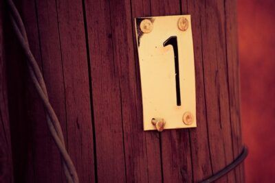 Placa con el número uno fijada en un poste de madera que significa el numero descubre su significado y simbolismo