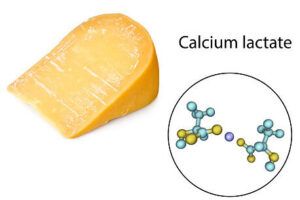 Pedazo de queso curado con puntos blancos visibles y diagrama molecular etiquetado como Calcium lactate que significa si el queso tiene puntos blancos descubre la verdad aqui.