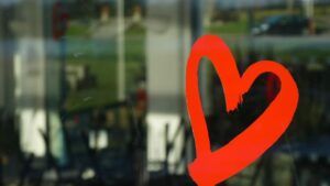 Corazón rojo pintado en vidrio que inspira búsquedas sobre que significa tatuaje corazon flecha brazo.