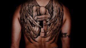 Tatuaje en la espalda de alas realistas que envuelven una figura humana; que significa tatuaje nube en clave simbólica