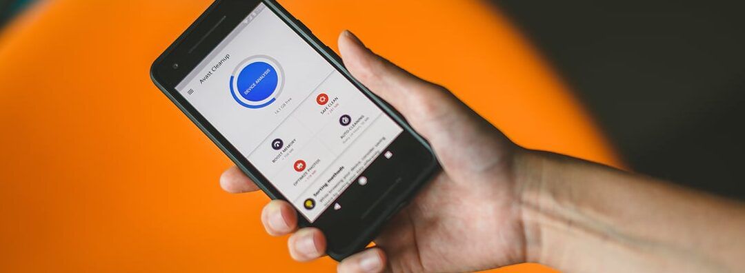 Mano sosteniendo un teléfono móvil con una app de limpieza en pantalla, que sucede al borrar un contacto del telefono antiguo descubre las consecuencias aqui