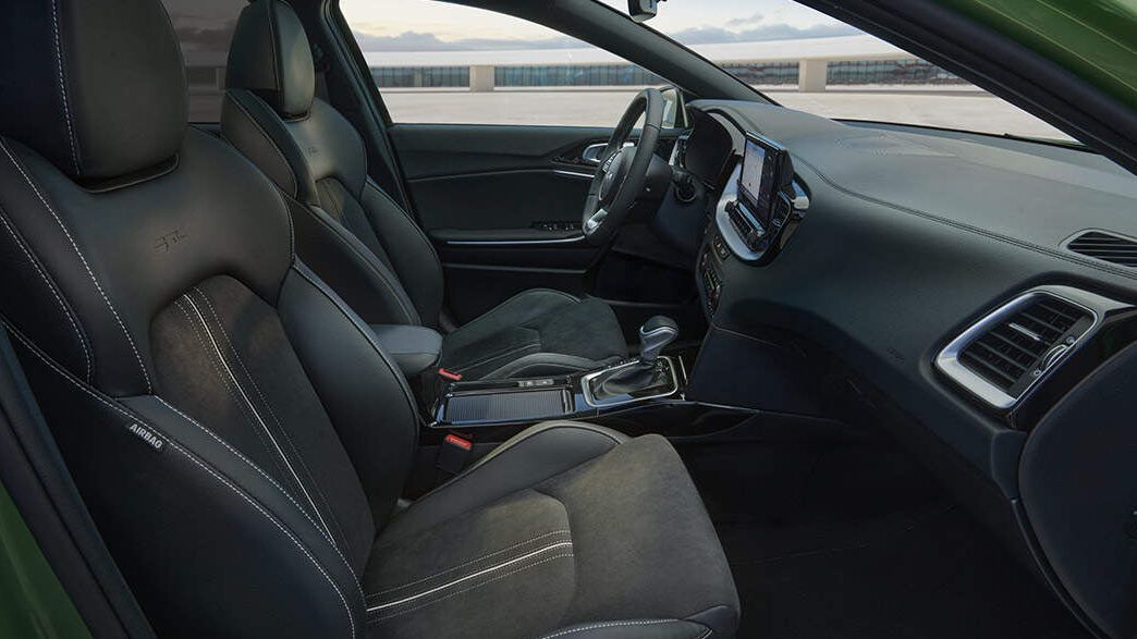 Interior delantero de un coche con asientos deportivos, volante multifunción y consola central táctil que sucede al combinar dos fases electricas descubrelo aqui