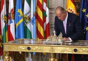 Monarca en traje formal firmando un documento sobre una mesa ceremonial, que sucede si el rey no firma una ley en espana