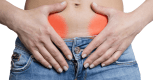 Persona con manos sobre la parte baja del abdomen y zonas enrojecidas que sugiere que sucede si un quiste se rompe consecuencias y tratamiento