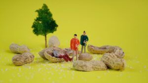 Miniaturas entre cáscaras de maní y cristales de sal sobre fondo amarillo, imagen conceptual para receta autentica aji gallina estilo republica.