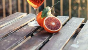Copa de cóctel naranja y mitades de naranja sanguina junto a receta clasica aperol spritz