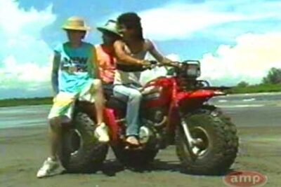 Tres personas en un quad en la playa con ropa mojada 1 sobre la arena.