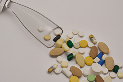 Frasco volcado con pastillas de distintos colores y formas que ilustra se puede tomar un medicamento caducado todo lo que necesitas saber.