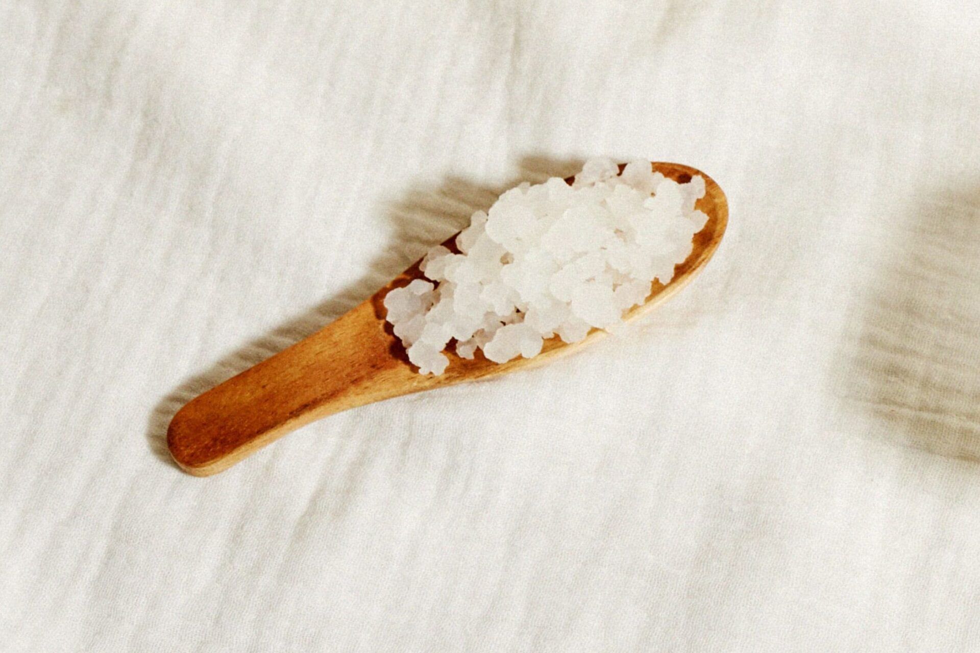 Granos blancos de kéfir en una cuchara de madera, secretos del kefir de leche aprende como usarlo despues de abrirlo