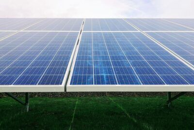 Paneles solares sobre soportes metálicos y césped que evocan el significado aplicaciones ponerse pilas en generación limpia.