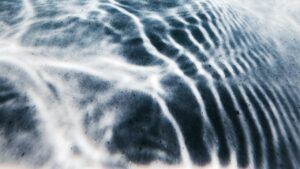 Patrón de ondas y reflejos en agua superficial con sombras y matices que sugieren el significado color azul marino