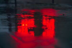 Reflejo difuso de luces rojas en pavimento mojado que evoca el significado color rojo.