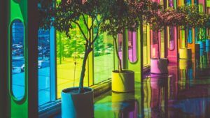 Corredor interior con árboles en macetas y paneles de vidrio multicolor que muestran el significado color rosa palo claro entre otros tonos