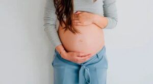 Mujer embarazada con las manos sobre el vientre en postura tranquila significado de estar en las nubes descubre su significado aqui 1
