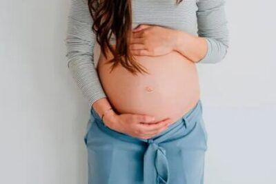 Mujer embarazada con las manos sobre el vientre en postura tranquila significado de estar en las nubes descubre su significado aqui 1