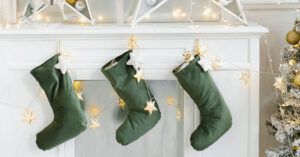 Tres botas navideñas verdes colgadas en una repisa blanca con luces de estrellas que evocan significado de ponerse las botas explicacion y origen 2.