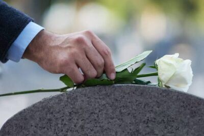 Mano colocando una rosa blanca sobre una lápida, evocando significado de sonar con ser enterrado vivo interpretacion y mas 1