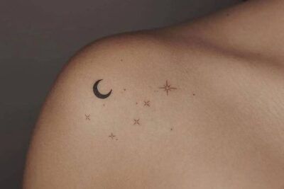 Significado de un tatuaje de luna y estrella en el cuello con una media luna negra y pequeñas estrellas minimalistas sobre la clavícula