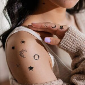 Composición de tatuajes minimalistas en tinta negra con luna, estrellas y soles que muestra el significado de un tatuaje de luna y estrella en la muneca.