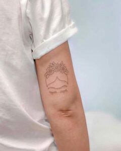 Tatuaje minimalista en el brazo con ojos cerrados, pestañas y corona de flores, significado del tatuaje de estrella en el cuello guia completa