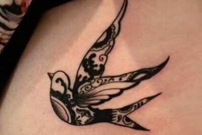 Golondrina tatuada en tinta negra con motivos ornamentales en la piel significado del tatuaje de golondrina descubre su simbolismo 1
