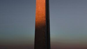 Columna vertical de concreto iluminada por una luz cálida al atardecer, textura y contraste, significado explicacion tatuaje cruz celta