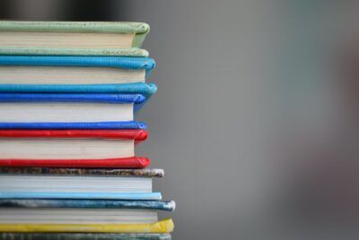 Pila de libros con lomos rojos, azules y amarillos que sugiere estudio y significado simbolismo sonar desnudo escuela