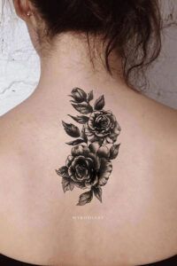 Tatuaje vertical en tinta negra de dos rosas con hojas y sombreado realista, interpretación del significado y simbolismo de un tatuaje de rosa en el pie 1.