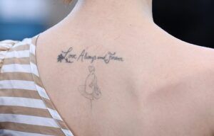 Tatuajes en la parte superior de la espalda con texto "Love Always and Forever" y una figura de bailarina minimalista, significado y simbolismo del tatuaje de cruz en brazo