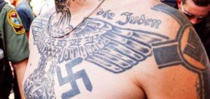 Torso con tatuajes de águila, esvástica y texto, enfoque en significado y simbolismo del tatuaje de cruz en el cuello 1