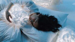 Persona dormida abrazando una nube luminosa sobre el pecho, simbolismo de sonar con ser abandonado por tu pareja 1