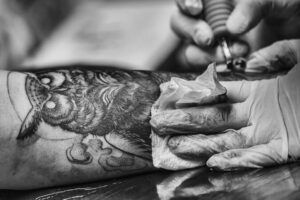 Simbolismo de un tatuaje de buho significado y poder 1 en un tatuaje de búho detallado en el antebrazo mientras el artista con guantes limpia la zona