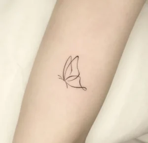 Tatuaje minimalista de mariposa en líneas finas sobre la piel, simbolismo del tatuaje de mariposa en la espalda significado y mas