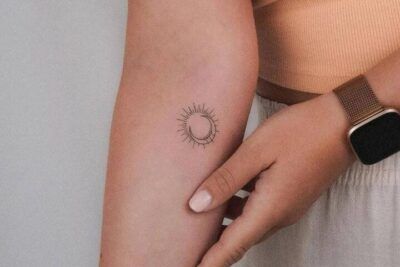 Tatuaje minimalista de media luna con rayos finos en el antebrazo que sugiere simbolismo y significado de un tatuaje de luna y estrella en el hombro 1.