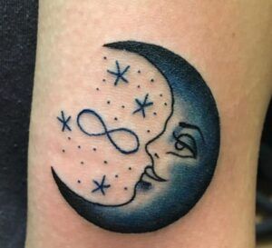 Tatuaje de media luna con rostro, estrellas y un símbolo infinito, simbolismo y significado de un tatuaje de luna y estrella en el hombro.