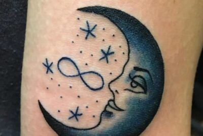 Tatuaje de media luna con rostro, estrellas y un símbolo infinito, simbolismo y significado de un tatuaje de luna y estrella en el hombro.