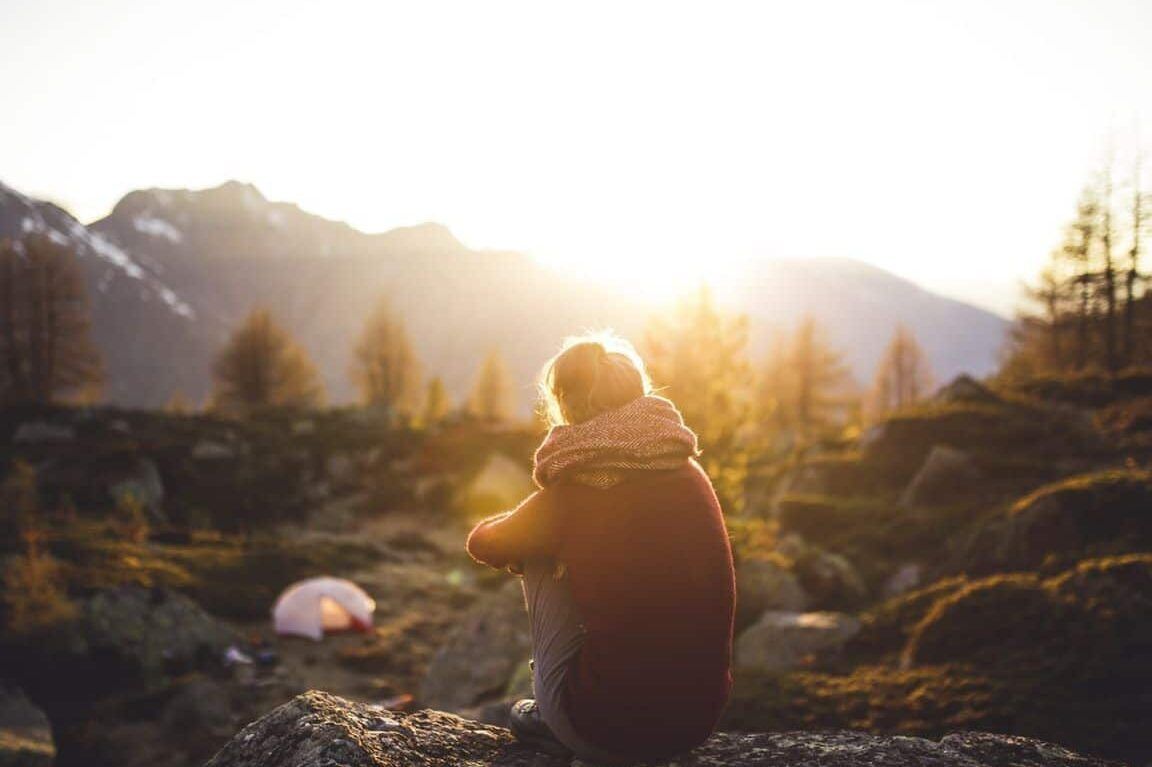 Persona sentada en una roca al atardecer en la montaña, imagen sugerente para sonar con estar perdido en un laberinto guia y explicacion