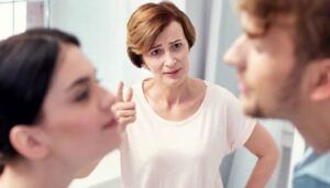Mujer de mediana edad con expresión crítica frente a pareja joven ilustrando sonar con perder todos los dientes significado y representacion