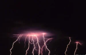 Relámpagos violetas descendiendo desde nubes oscuras, evocando sonar con un tsunami de lava significado y interpretacion
