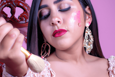 Mujer aplicando maquillaje con brocha sobre la mejilla y ojos cerrados, su sesion ha caducado por favor ingrese nuevamente