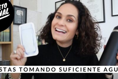 Mujer sonriente sosteniendo una botella negra y una ilustración de vaso preguntando si toma suficiente agua.