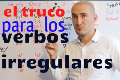 Profesor frente a un pizarrón con listas de verbos irregulares y el texto 'el truco para los verbos irregulares' tETVgL UGMI