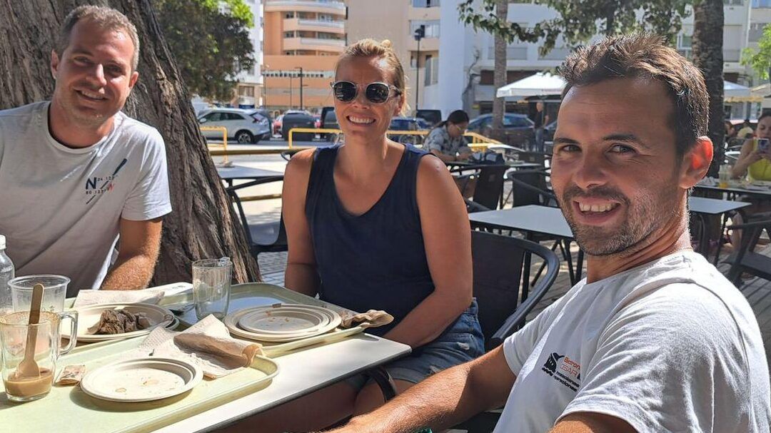 Tres personas sonrientes sentadas en una terraza con platos y vasos, te toco ser miembro de una mesa electoral descubre que hacer en esta situacion