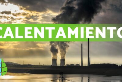 Planta industrial junto a un embalse con torres de refrigeración y chimeneas que emiten vapor y humo bajo cielos nublados, representando el calentamiento umAGi80FsPM.