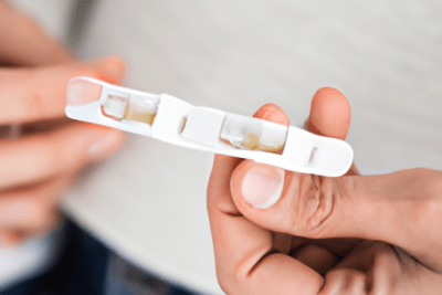 Mano sosteniendo un test de embarazo en primer plano, una prueba de embarazo caducada sirve descubre la verdad aqui.