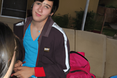 Joven sentado junto a una mochila rosa en un sofá al aire libre, ver si mi bono esta caducado todo lo que necesitas saber.